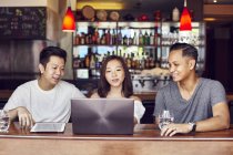 Щасливі молоді азіатські друзі разом працюють з ноутбуком в барі — стокове фото