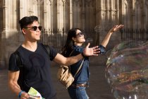Chinese couple in Barcelona playing with soap bubbles, Spain — Stock Photo