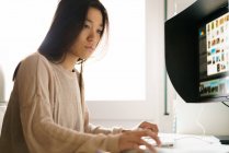 Chinese woman working from home at computer — Stock Photo
