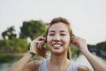 Young asian woman listening to music in earpods — Stock Photo