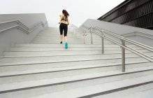 A young asian, female runner is running up a staircase in Singapore. — Stock Photo