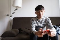 Молодий дорослий азіатський чоловік грає у відеоігри вдома — стокове фото