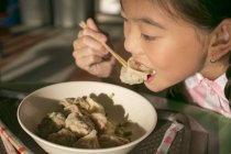 Маленька азіатська дівчина їсть їжу в кафе — стокове фото