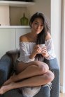 Jovem chinesa em um sofá bebendo café — Fotografia de Stock