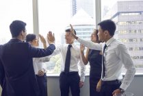 Молоді азіатські бізнесменів даючи п'ять під сучасні офісні — стокове фото