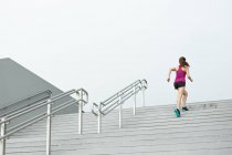 Un giovane asiatico, corridore femminile sta correndo su per una scala a Singapore . — Foto stock