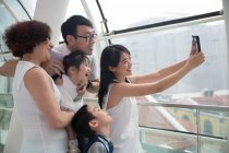 Una familia asiática de tres generaciones se toma una selfie en un centro comercial - foto de stock