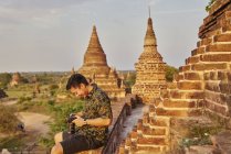 Joven tomando fotos alrededor del antiguo templo de Pyathadar, Bagan, Myanmar - foto de stock