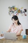 Junge beiläufige asiatische Frau mit Laptop zu Hause — Stockfoto