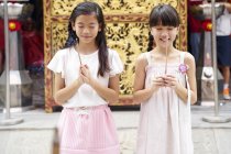 Feliz asiático irmãs orando juntos no tradicional cingapuriano santuário — Fotografia de Stock