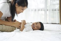 Asiatico madre bonding con il suo figlio su il letto — Foto stock
