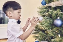 Piccolo asiatico ragazzo decorazione abete — Foto stock