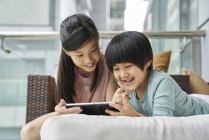 Glückliche junge asiatische Jungen und Mädchen zusammen mit digitalem Tablet zu Hause — Stockfoto