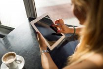 Retrato de una hermosa joven usando su tableta digital en la cafetería . - foto de stock