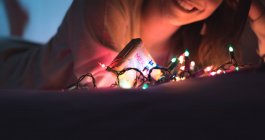 Joven mujer asiática relajándose en casa con guirnalda de Navidad - foto de stock