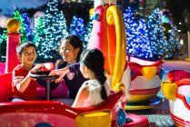 Happy asian siblings spending time together in amusement park at christmas — Stock Photo