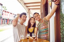 Felice giovani amici asiatici in bar insieme prendendo selfie — Foto stock