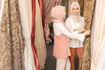 Dos musulmanas en una tienda comprando cortinas - foto de stock