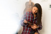 Chinês mulher tocando seu ukulele em casa — Fotografia de Stock