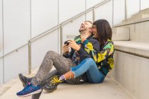 Joven atractivo multirracial pareja sentado en escaleras - foto de stock