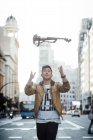 Joven asiático músico macho lanzando violín en el aire en ciudad - foto de stock