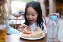Menina chinesa feliz olhando para seu pão com presunto — Fotografia de Stock
