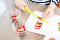 Abgeschnittenes Bild einer Frau, die zu Hause Erdbeeren schneidet — Stockfoto