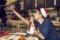 Junges asiatisches Paar macht Selfie in Weihnachtsmannhüten — Stockfoto