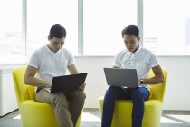 Молоді азіатські бізнесмени працюють з ноутбуками в сучасному офісі — стокове фото