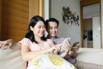Доросла азіатська пара разом використовує смартфони вдома — стокове фото