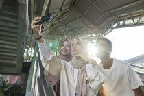 Grupo de amigos musulmanes felices tomando selfie en el teléfono inteligente - foto de stock