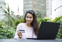Schöne malaiische Dame, die einen Online-Kauf mit ihrer Kreditkarte tätigt — Stockfoto