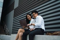 Pareja joven asiática de negocios que trabaja con ordenador portátil - foto de stock