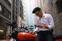 Jovem empresário asiático na cidade usando celular — Fotografia de Stock