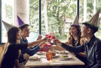 Счастливые молодые люди и их друзья вместе празднуют Новый год в кафе — стоковое фото