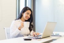 Junge Frau mit einer Tasse Kaffee in der Hand im modernen Büro — Stockfoto