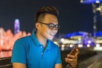 Jeune homme jouant avec son smartphone en ville — Photo de stock