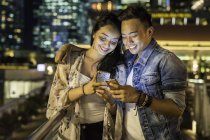 Молодая пара играет со смартфоном в городе — стоковое фото