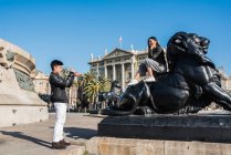 Pareja de turistas jóvenes tomando fotos en el monumento de Colón con el teléfono móvil, España - foto de stock