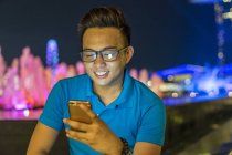 Молодой человек играет со своим смартфоном в городе — стоковое фото