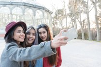 Amigos tomando selfies en Parque del Retiro Madrid, España - foto de stock