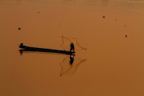 Одинокий рыбак закидывает сеть — стоковое фото
