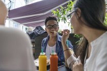 Young beautiful asian friends eating in cafe — Stock Photo