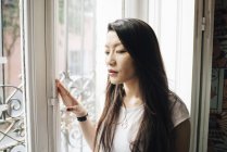 Atraente asiático mulher olhando fora de janela — Fotografia de Stock