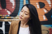 Portrait of attractive asian woman against graffiti — Stock Photo