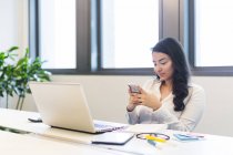 Junge Frau arbeitet mit ihrem Handy im modernen Büro — Stockfoto