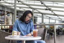 Junge Frau notiert in einem Café ein paar Informationen. — Stockfoto
