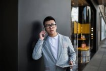 Китайський бізнесмен, говорити по телефону на вулиці поруч із розкішному магазині на вулиці Серрано, Мадрид, Іспанія — стокове фото