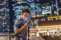 Молодий чоловік грає зі своїм смартфоном у місті — стокове фото