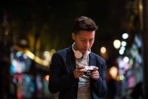 Casual young chinese man hanging around in the streets of Madrid at night with camera, Spain — Stock Photo
